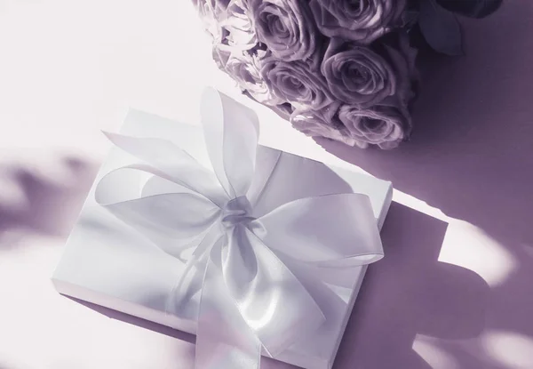 Luxo feriado caixa de presente de seda e buquê de rosas em roxo de volta — Fotografia de Stock