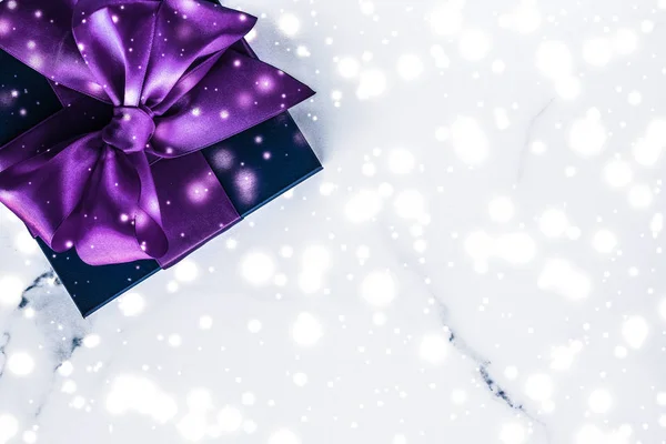 Зимний праздник подарочная коробка с фиолетовым шелковым луком, снежные блестки на ма — стоковое фото