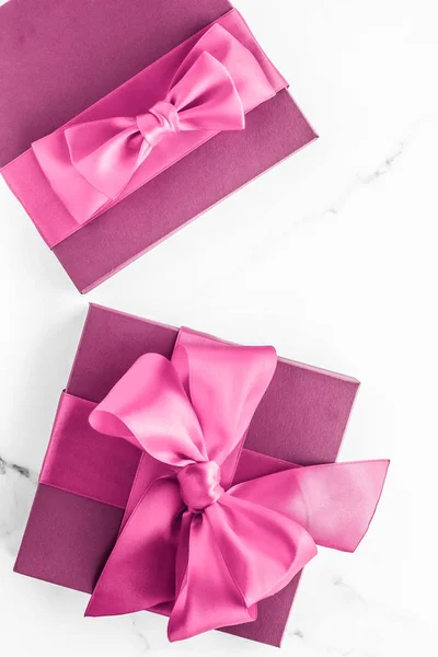 Pink gift box with silk bow on marble background, girl baby show