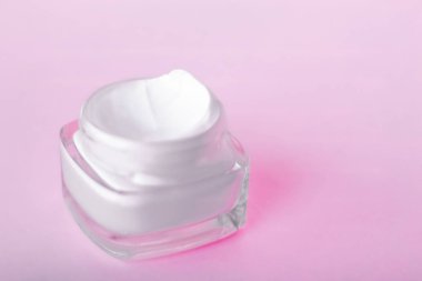 Pembe arka planda yüz kremi nemlendirici kavanozu, nemlendirici cilt