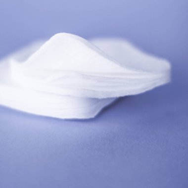 Mor arka planda organik pamuk pedleri, kozmetik ürünleri ve makyaj 