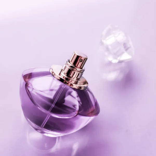 Фіолетова пляшка парфумів на глянсовому фоні, солодкий квітковий запах , — стокове фото