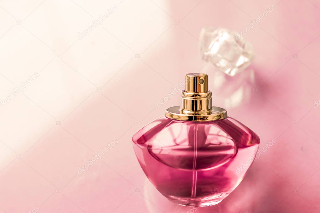 Pink perfume bottle on glossy background, sweet floral scent, gl