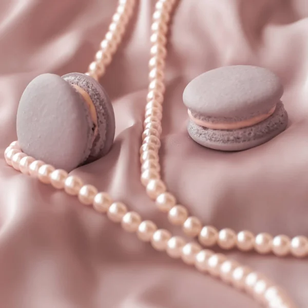 Sweet macaroons and pearls jewellery on silk background, parisia