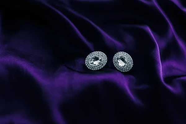 Розкішні діамантові сережки на темно-фіолетовій шовковій тканині, святковий блиск — стокове фото