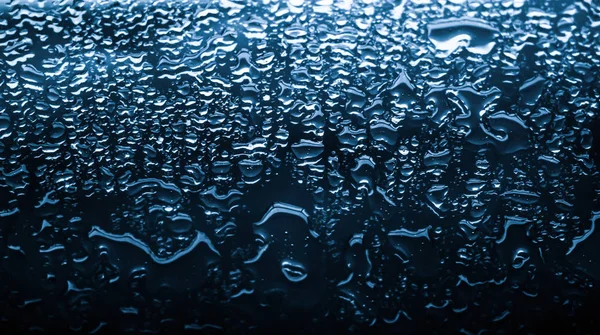 水的质感抽象的背景，水滴落在蓝色的玻璃杯上 — 图库照片