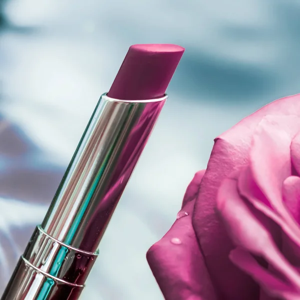 Purple lipstick and rose flower on liquid background, waterproof