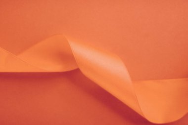 Turuncu arka planda soyut kıvrımlı ipek kurdele, özel lüks.