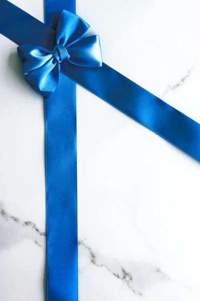 Блакитна шовкова стрічка і лук на розкішному мармуровому фоні, святковий фл — стокове фото