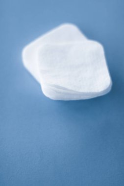 Mavi arka planda organik pamuk pedleri, kozmetik ürünleri ve makyaj malzemesi