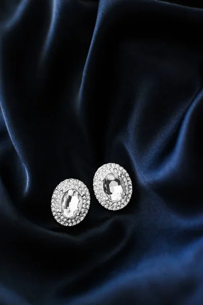 Luxusní diamantové náušnice na tmavomodré hedvábné pozadí, prázdninové GL — Stock fotografie