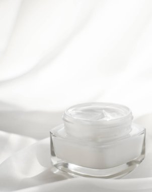 İpek arka planda yüz kremi nemlendirici kavanozu, nemlendirici cilt