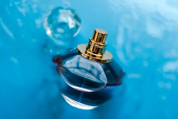 Garrafa de perfume sob água azul, cheiro costeiro de mar fresco como glam — Fotografia de Stock