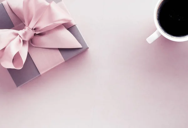 Luxury gift box and coffee cup on blush pink background, flatlay
