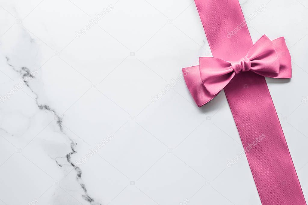 Pink silk ribbon and bow on marble background, girl baby shower 