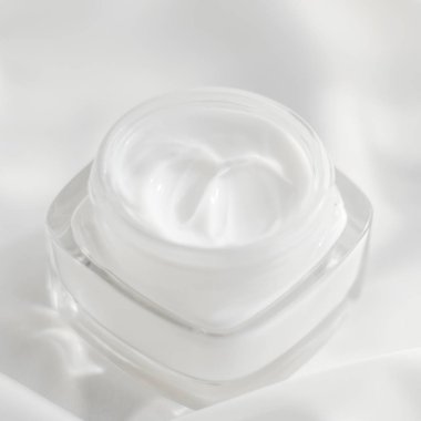 İpek arka planda yüz kremi nemlendirici kavanozu, nemlendirici cilt