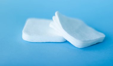 Mavi arka planda organik pamuk pedleri, kozmetik ürünleri ve makyaj malzemesi