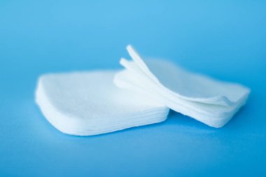 Mavi arka planda organik pamuk pedleri, kozmetik ürünleri ve makyaj malzemesi