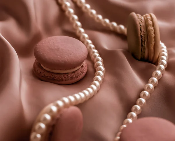 Söta makaroner och pärlor smycken på silke bakgrund, parisia — Stockfoto