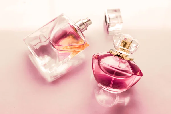 Pink perfume bottle on glossy background, sweet floral scent, gl