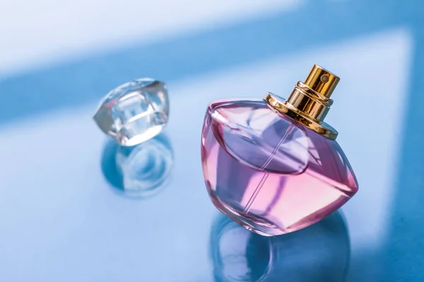 Pink perfume bottle on glossy background, sweet floral scent, gl