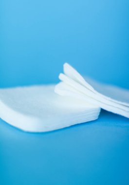 Mavi arka planda organik pamuk pedleri, kozmetik ürünleri ve makyaj malzemesi