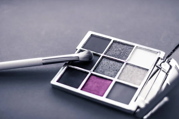 Eyeshadow palette and make-up brush on graphite background, eye