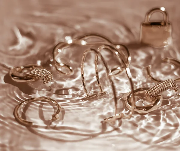 Gouden armbanden, oorbellen, ringen, sieraden op goud water backgr — Stockfoto