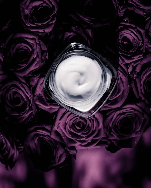 Crema facial hidratante de piel sobre rosas púrpuras flores, piel de lujo — Foto de Stock