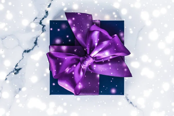 Winter holiday gift box with purple silk bow, snow glitter on ma — Stock Photo, Image