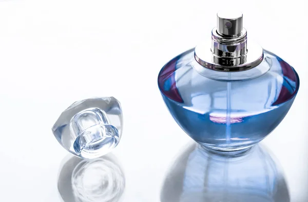 Niebieska butelka perfum na błyszczącym tle, słodki kwiatowy zapach, gl — Zdjęcie stockowe