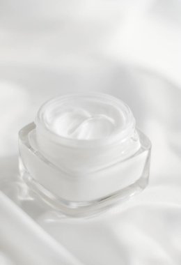 İpek arka planda yüz kremi nemlendirici kavanozu, nemlendirici cilt