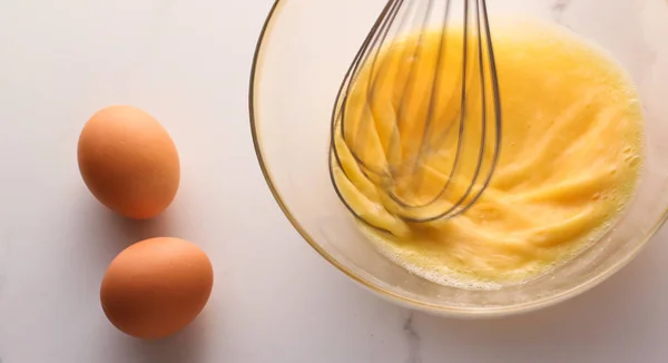 Membuat telur campur dalam mangkuk di atas meja marmer sebagai makanan buatan sendiri f — Stok Foto