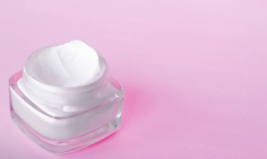 Pembe arka planda yüz kremi nemlendirici kavanozu, nemlendirici cilt