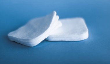 Mavi arka planda organik pamuk pedleri, kozmetik ürünleri ve makyaj malzemesi