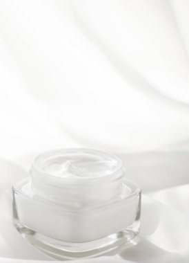 İpek arka planda yüz kremi nemlendirici kavanozu, nemlendirici cilt