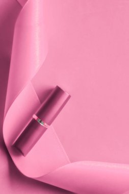 Pembe tatil arka planında lüks ruj ve ipek kurdele.