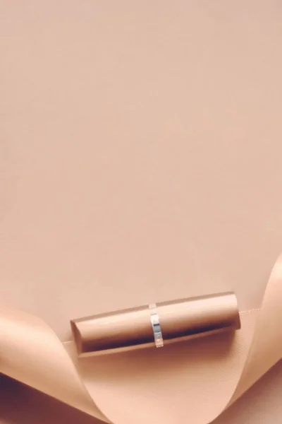 Lápiz labial de lujo y cinta de seda sobre fondo de fiesta beige, mak — Foto de Stock
