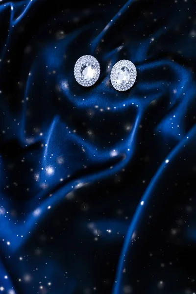 Роскошные бриллиантовые серьги на темно-синем шелке с блестками от снега, хол — стоковое фото
