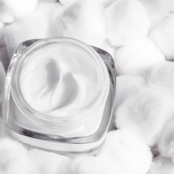 Luxury face cream for sensitive skin and white cotton balls on b