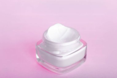 Pembe arka planda yüz kremi nemlendirici kavanozu, nemlendirici cilt