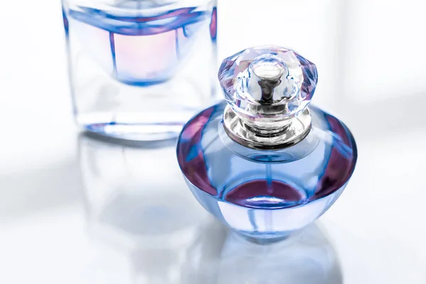 Синя пляшка парфумів на глянсовому фоні, солодкий квітковий запах, глянцевий — стокове фото