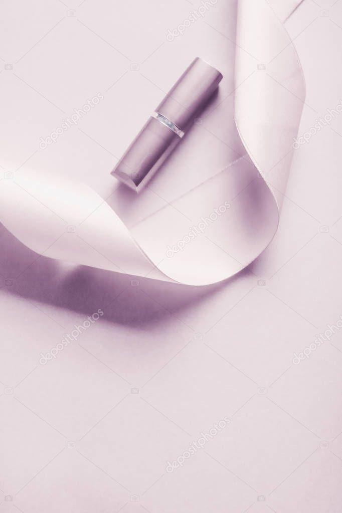 Luxury lipstick and silk ribbon on blush purple holiday backgrou