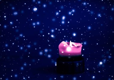 Mavi köpüklü kar arka plan üzerinde pembe tatil mum, lüks