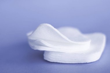 Mor arka planda organik pamuk pedleri, kozmetik ürünleri ve makyaj 