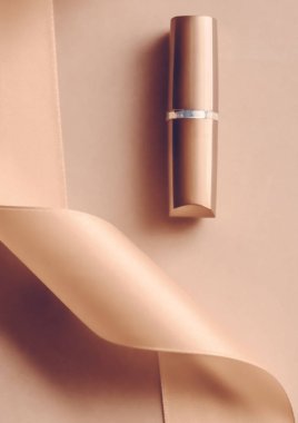 Bej rengi tatil arkaplanında lüks ruj ve ipek kurdele, mak