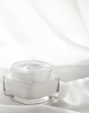 İpek arka planda yüz kremi nemlendirici kavanozu, nemlendirici cilt