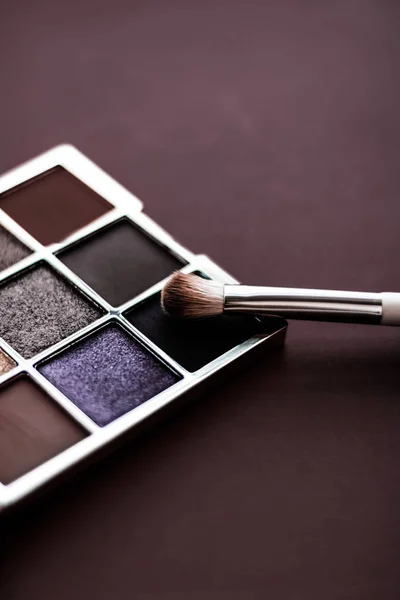 Eyeshadow palette and make-up brush on chocolate background, eye