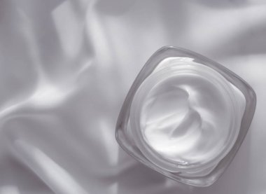 İpek arka planda yüz kremi nemlendirici kavanozu, nemlendirici cilt