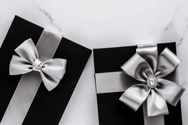 Luksusowe prezenty na święta ze srebrną wstążką jedwabiu i kokardą na marmurze b — Zdjęcie stockowe